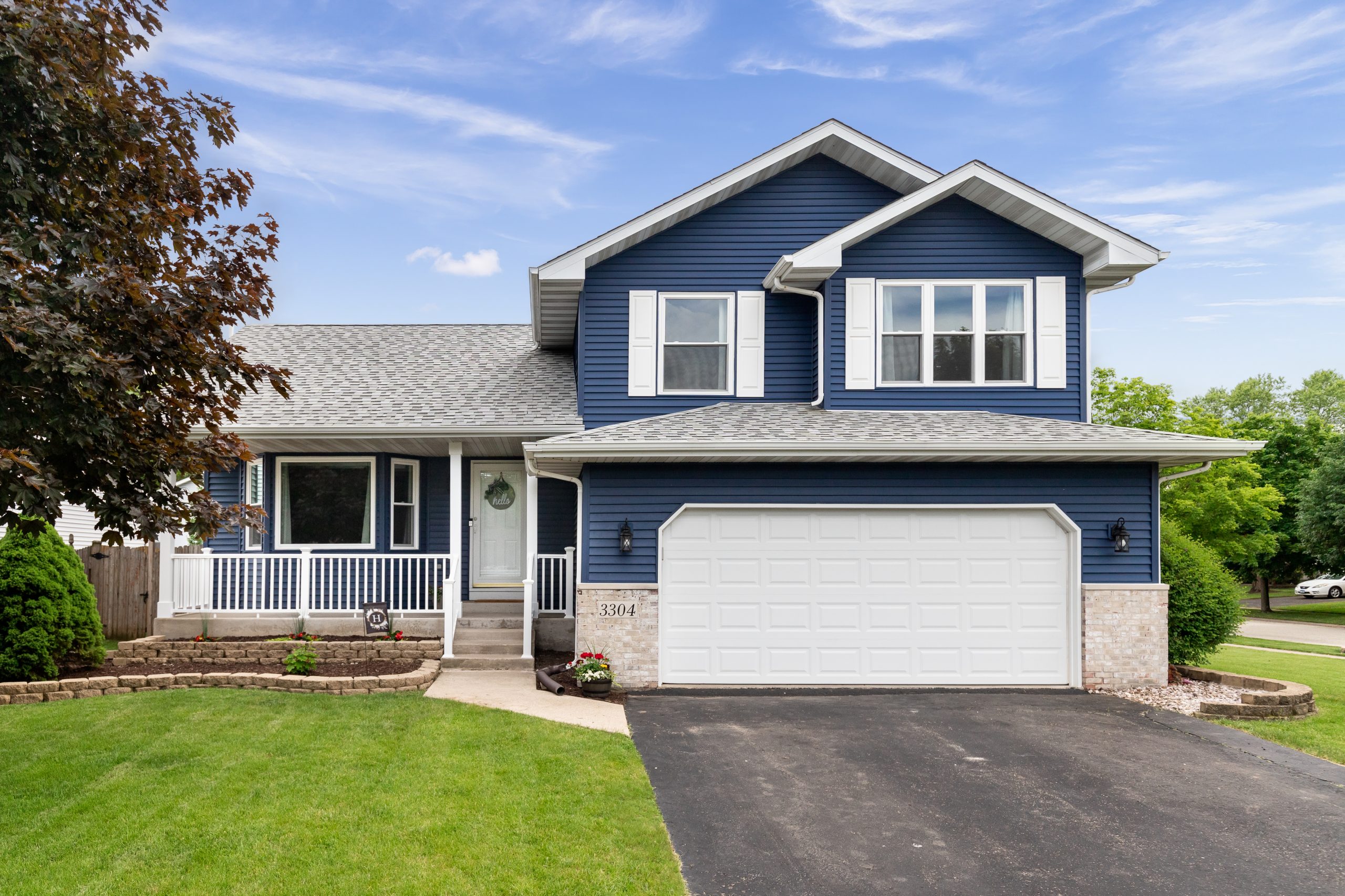 Exterior of a suburban home with blue siding, a white front porc Exterior of a suburban home with blue siding, a white front porc